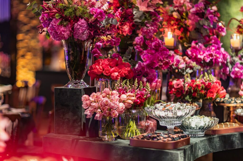 Opulent display of colorful floral arrangements with candles and desserts, perfect for celebrations.