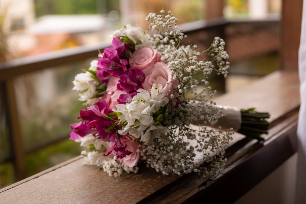 Vibrant bridal bouquet with pink roses and white lilies resting on a balcony.