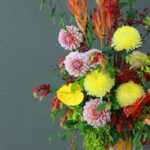 Vibrant floral arrangement in a decorative vase against a neutral background.