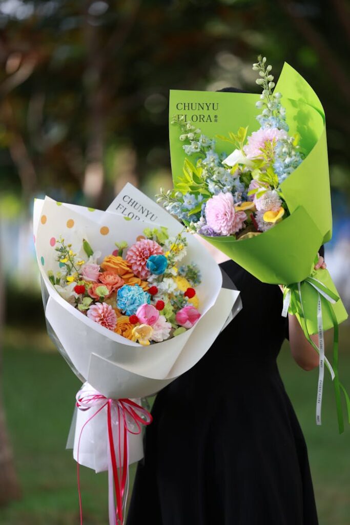 Vibrant flower bouquets held by a person in a lush outdoor setting, showcasing elegance.