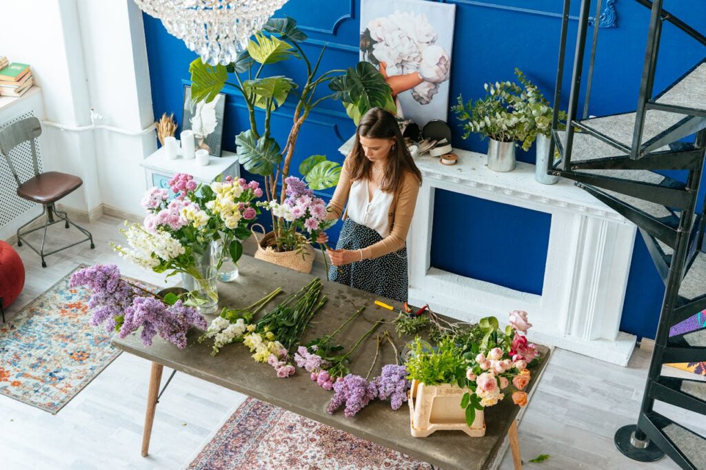 A florist in a stylish studio arranging a variety of fresh flowers on a table.